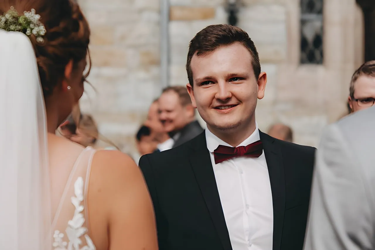 Dominik singt im Anzug mit Mikrofon vor dem Altarraum